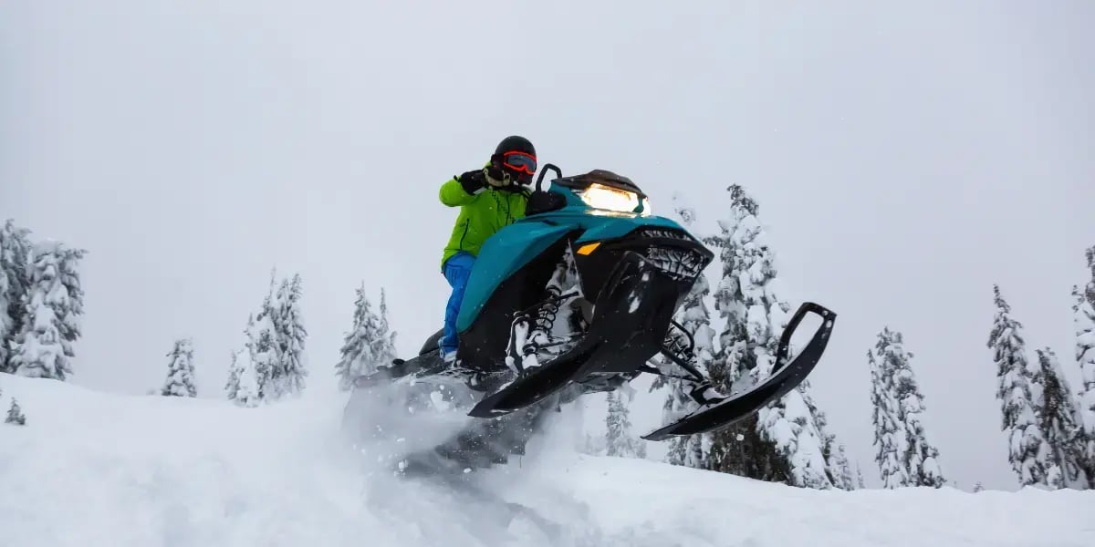 Adventurous Man Riding a Snowmobile in white snow