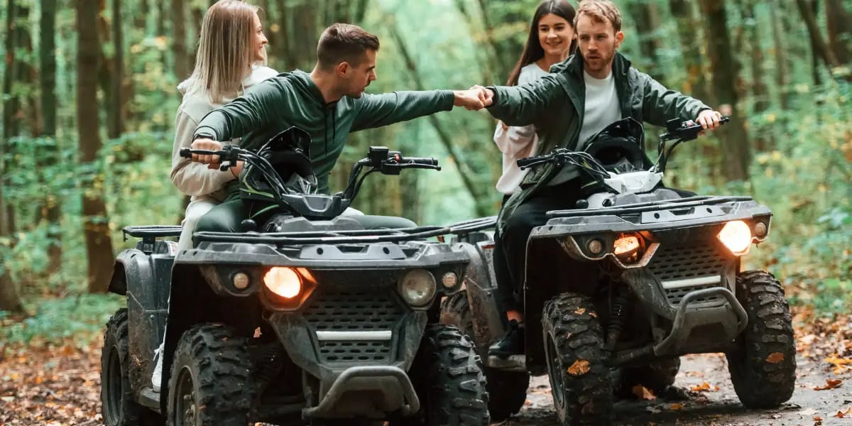 Two couples on a quad bike in the forest during the day