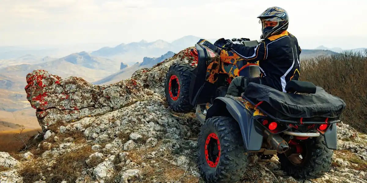 Adventurous Adult Riding ATV on Mountain Top