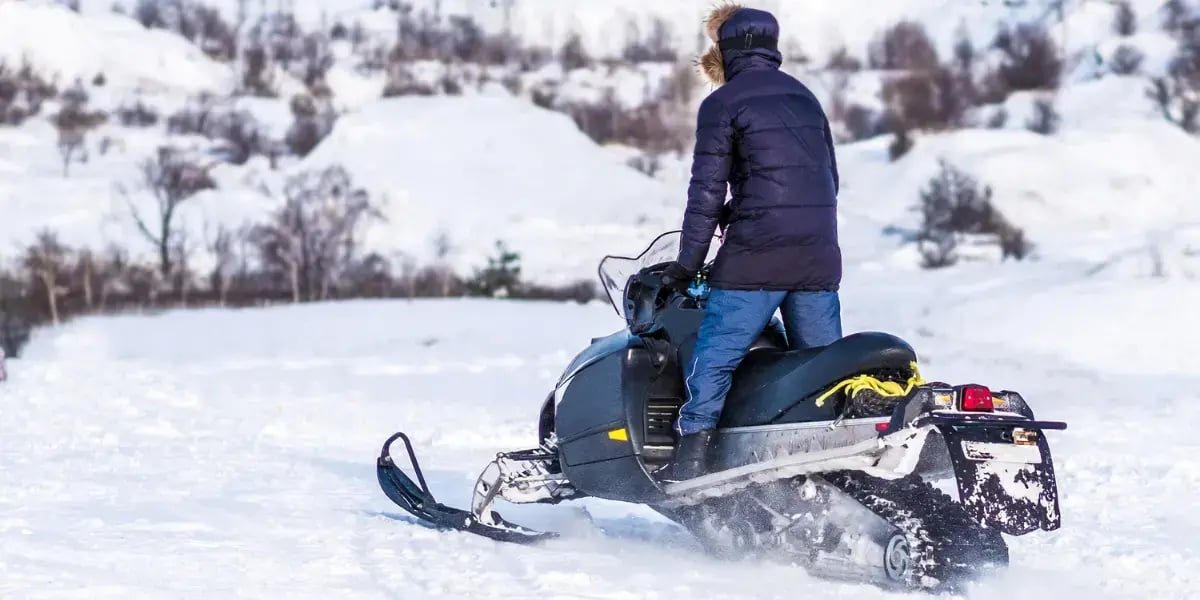 Winter Fun: Adult Riding Snowmobile in Snowy Landscape