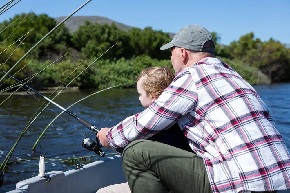 Happy man fishing with his son in the boat